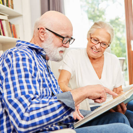 Older adult male and female smiling as they look at a scrapbook together