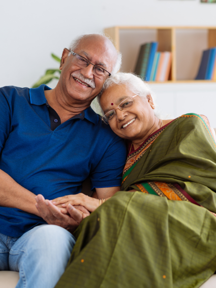 Smiling elderly couple holding hands and sitting together on a sofa